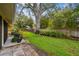 A fenced backyard features lush green grass, mature shade trees, and is partially shaded at 1930 Peppermill Dr, Clearwater, FL 33763
