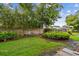 A fenced backyard has lush green grass, mature shade trees and landscaped borders at 1930 Peppermill Dr, Clearwater, FL 33763