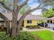 The front exterior is of a quaint house with carport and shade trees at 1930 Peppermill Dr, Clearwater, FL 33763