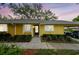 Charming single-story home with yellow exterior, manicured landscaping, and a convenient carport at 1930 Peppermill Dr, Clearwater, FL 33763