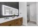 Modern bathroom with dual sinks, wood cabinets, a lighted mirror, and a glass-enclosed shower at 2182 Wisteria St, Sarasota, FL 34239