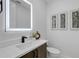 Modern half bath featuring an illuminated mirror, stylish vanity, and elegant decor at 2182 Wisteria St, Sarasota, FL 34239