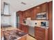 Modern kitchen showcasing cherry wood cabinets, stainless appliances, granite counters, and tile backsplash at 226 Golden Gate Pt # 63, Sarasota, FL 34236