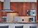 Close-up of kitchen with cherry wood cabinets, tile backsplash, stainless microwave, and granite countertop at 226 Golden Gate Pt # 63, Sarasota, FL 34236