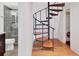 Unique spiral staircase with wood treads connects levels, offering modern style near the bathroom and laundry room at 226 Golden Gate Pt # 63, Sarasota, FL 34236