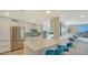 Modern kitchen with sleek white cabinets, stainless steel appliances, and a breakfast bar overlooking the ocean at 2425 Gulf Of Mexico Dr # 6A, Longboat Key, FL 34228