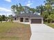 Charming single-story home with a well-manicured lawn and a driveway leading to a two-car garage at 2704 Gaspar Ave, North Port, FL 34288