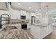 Well-lit kitchen with white cabinets, granite counters, stainless steel appliances, and a kitchen island at 2704 Gaspar Ave, North Port, FL 34288