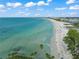 Expansive beach view with clear turquoise water, a sandy shore, and distant buildings under a sunny sky at 302 And 304 Canal Rd, Sarasota, FL 34242