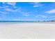 Expansive white sand beach with scattered beachgoers and calm, clear water under a bright blue sky with scattered clouds at 302 And 304 Canal Rd, Sarasota, FL 34242