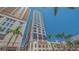 Exterior view of a high rise condo with multiple stories and balconies, framed by lush palm trees against a blue sky at 33 S Palm Ave # 1303, Sarasota, FL 34236