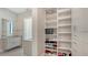 Bright walk-in closet features custom shelves, a shoe rack, and integrates with a modern bathroom at 33 S Palm Ave # 1303, Sarasota, FL 34236