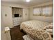 Bedroom with dark wood floors, tan patterned bedding, and a closet with a TV at 3318 Oakwood S Blvd, Sarasota, FL 34237