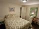 Bedroom with tan patterned bedding, wood floors, and a view into the hallway at 3318 Oakwood S Blvd, Sarasota, FL 34237