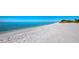 Expansive beach view showcases soft white sand meeting the clear blue ocean under a sunny sky at 3320 Gulf Of Mexico Dr # 208C, Longboat Key, FL 34228