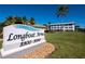 Well-maintained Longboat Arms community with manicured lawn, mature trees, and clear blue skies at 3320 Gulf Of Mexico Dr # 208C, Longboat Key, FL 34228