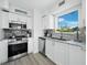Modern kitchen with stainless steel appliances, white cabinets, and a window overlooking lush greenery at 3320 Gulf Of Mexico Dr # 208C, Longboat Key, FL 34228