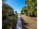 A concrete walkway winds through lush foliage, leading to a pristine beach with stunning ocean views at 3320 Gulf Of Mexico Dr # 208C, Longboat Key, FL 34228