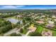 Aerial view of a well-manicured home with a screened-in pool, near a lake, surrounded by lush greenery at 385 165Th Ne Ct, Bradenton, FL 34212
