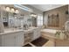 Bright bathroom featuring dual sinks, vanity, large mirror, soaking tub, and decorative fixtures at 385 165Th Ne Ct, Bradenton, FL 34212
