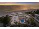 Aerial view of beachfront property with a pool, palm trees, and amazing ocean views at sunset at 4200 Gulf Dr # 104, Holmes Beach, FL 34217