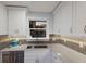 Close up of the modern kitchen featuring stainless steel appliances, stone countertops and grey tiled backsplash at 4200 Gulf Dr # 104, Holmes Beach, FL 34217