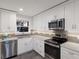 Modern kitchen featuring white cabinets, stainless steel appliances, gray tile backsplash, and stone countertops at 4200 Gulf Dr # 104, Holmes Beach, FL 34217