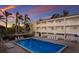 Community pool with sun loungers surrounded by palm trees and a multi-story condo building in the background at 4200 Gulf Dr # 104, Holmes Beach, FL 34217
