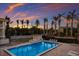 Relaxing outdoor pool area surrounded by palm trees and lounge chairs under a beautiful sunset sky at 4200 Gulf Dr # 104, Holmes Beach, FL 34217