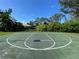 Outdoor basketball court with green surface, white lines, hoop, and lush green surrounding trees, offering recreational opportunities at 4239 Corso Venetia Blvd, Venice, FL 34293