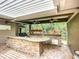 The outdoor kitchen provides a stainless-steel grill, granite countertops, a stone bar, and outdoor views at 4239 Corso Venetia Blvd, Venice, FL 34293