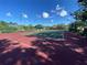 Well-maintained tennis court with green and red surfaces, lighting, and surrounding trees at 4239 Corso Venetia Blvd, Venice, FL 34293