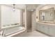 Elegant bathroom featuring a soaking tub, a glass shower, a chandelier, and vanity with great lighting at 4584 Tuscana Dr, Sarasota, FL 34241