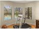 Bright bedroom with a treadmill, three large windows overlooking a swimming pool and green trees at 4584 Tuscana Dr, Sarasota, FL 34241