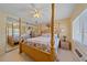 Bright bedroom featuring a wooden four-poster bed, mirrored closet and a ceiling fan at 475 Benjamin Franklin Dr # 211, Sarasota, FL 34236