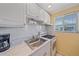 Close-up of kitchen with stainless steel sink, electric range, and white tile backsplash at 475 Benjamin Franklin Dr # 211, Sarasota, FL 34236