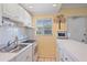 Compact kitchen featuring white cabinetry, tile backsplash, and modern appliances, providing a functional cooking space at 475 Benjamin Franklin Dr # 211, Sarasota, FL 34236