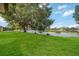Spacious green lawn sloping down to a picturesque lake view under a blue sky with scattered clouds at 5091 Creekside Trl, Sarasota, FL 34243