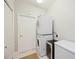 A laundry room featuring stacked washer and dryer units and tiled flooring near the storage door at 5091 Creekside Trl, Sarasota, FL 34243