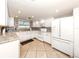 A kitchen features all white appliances, ample cabinetry, granite countertops, and tile flooring at 5669 Midnight Pass Rd # 308, Sarasota, FL 34242
