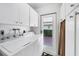 Well-lit laundry room equipped with modern appliances, white cabinets, and access to the outside at 6422 Auburn Ave, Bradenton, FL 34207