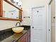 Stylish bathroom with a dark granite countertop and unique decorative bamboo mirror at 7320 Melaleuca Way, Siesta Key, FL 34242