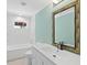 Bright bathroom featuring tiled walls, large mirror, vanity and a tub with shower at 7320 Melaleuca Way, Siesta Key, FL 34242