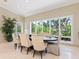 Inviting dining room with natural light, travertine floors, and lush landscaping at 7320 Melaleuca Way, Siesta Key, FL 34242