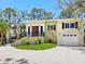 Charming light yellow two-story home with lush landscaping and a red front door at 7320 Melaleuca Way, Siesta Key, FL 34242