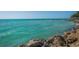 Stunning turquoise ocean view with rocky shoreline and distant sailboat at 7320 Melaleuca Way, Siesta Key, FL 34242