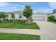 Charming home featuring a well-manicured lawn, mature landscaping, and a paved driveway leading to the garage at 7717 Sandhill Lake Dr, Sarasota, FL 34241