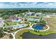 Aerial image displays community amenities: swimming pools, playgrounds, and tennis courts by a lake at 7885 Bristol Park Dr, Apollo Beach, FL 33572