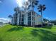 Condominium exterior featuring beautiful palm trees, landscaping and blue skies at 7911 Grand Estuary Trl # 201, Bradenton, FL 34212