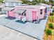 Unique, pink home with black and white striped awnings and a modern driveway design at 8 Desoto E St, Bradenton, FL 34208